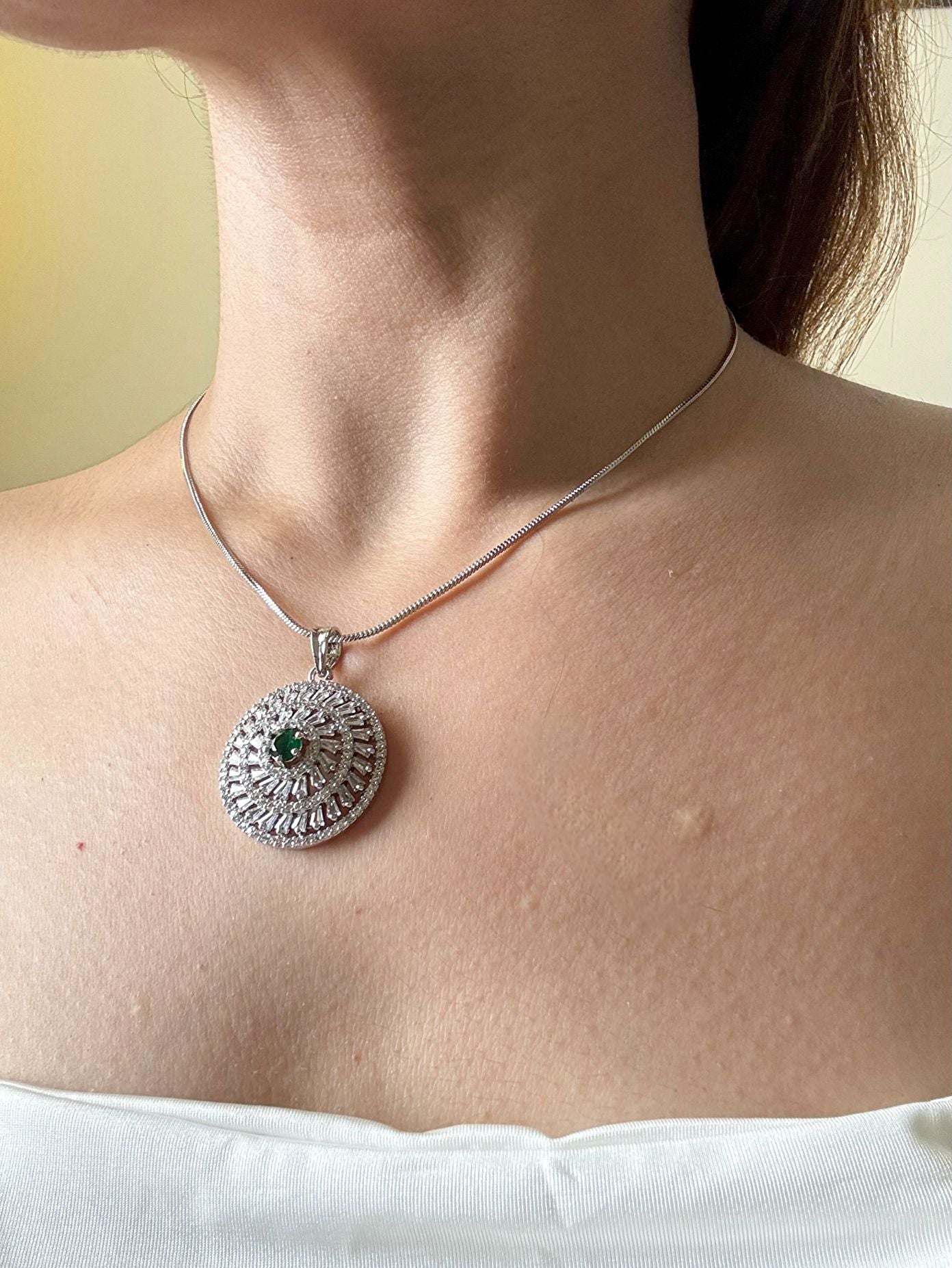 Shop Kiara Round Pendant Set With Studs In AD & Green Stone Online in India. Pendant sets in different stones like Kundan, Moissanite, CZ stones and AD stones in all kinds quality are available online for purchase on website. Explore pendant sets for festive occasions perfect mothers and elderly ladies too. Pendant sets in green, blue, pink, red and white stones are available for wearing with sarees, lehengas, suits and Indo-westerns. -side