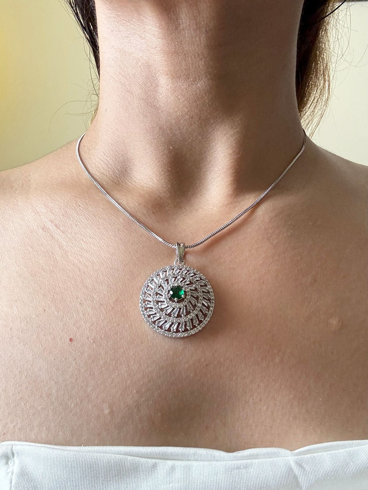Shop Kiara Round Pendant Set With Studs In AD & Green Stone Online in India. Pendant sets in different stones like Kundan, Moissanite, CZ stones and AD stones in all kinds quality are available online for purchase on website. Explore pendant sets for festive occasions perfect mothers and elderly ladies too. Pendant sets in green, blue, pink, red and white stones are available for wearing with sarees, lehengas, suits and Indo-westerns. -withearrings